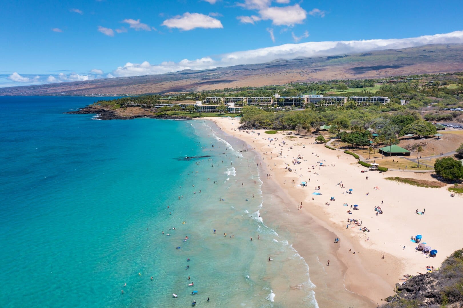 Crowded beach with turquoise waters.