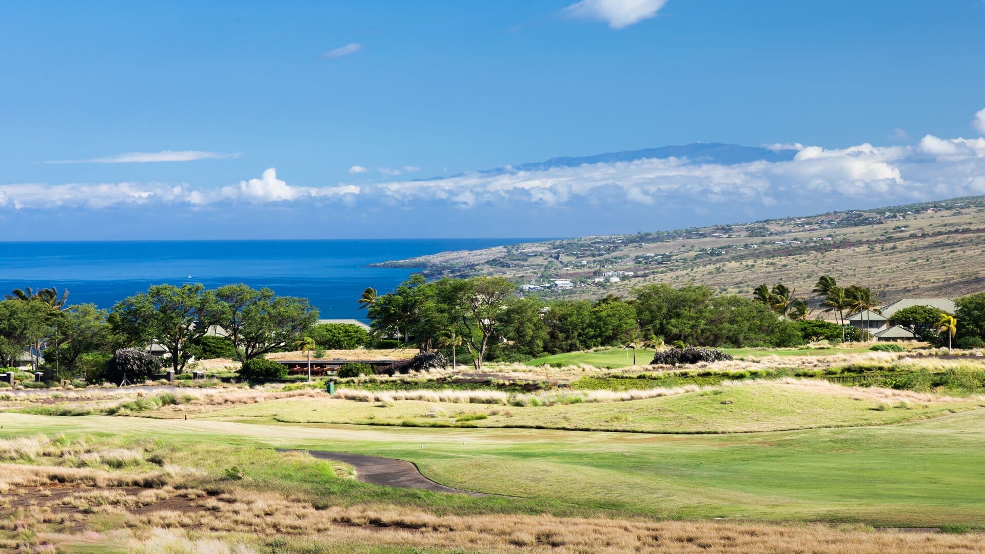 Golf course with ocean and hills.