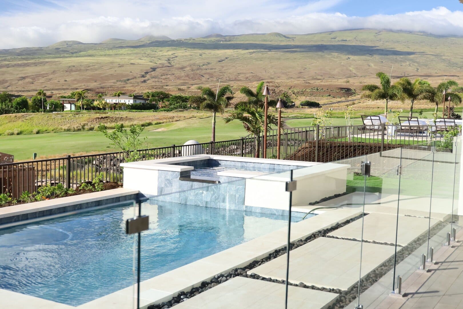 Pool, fence, lawn, hills, sky.