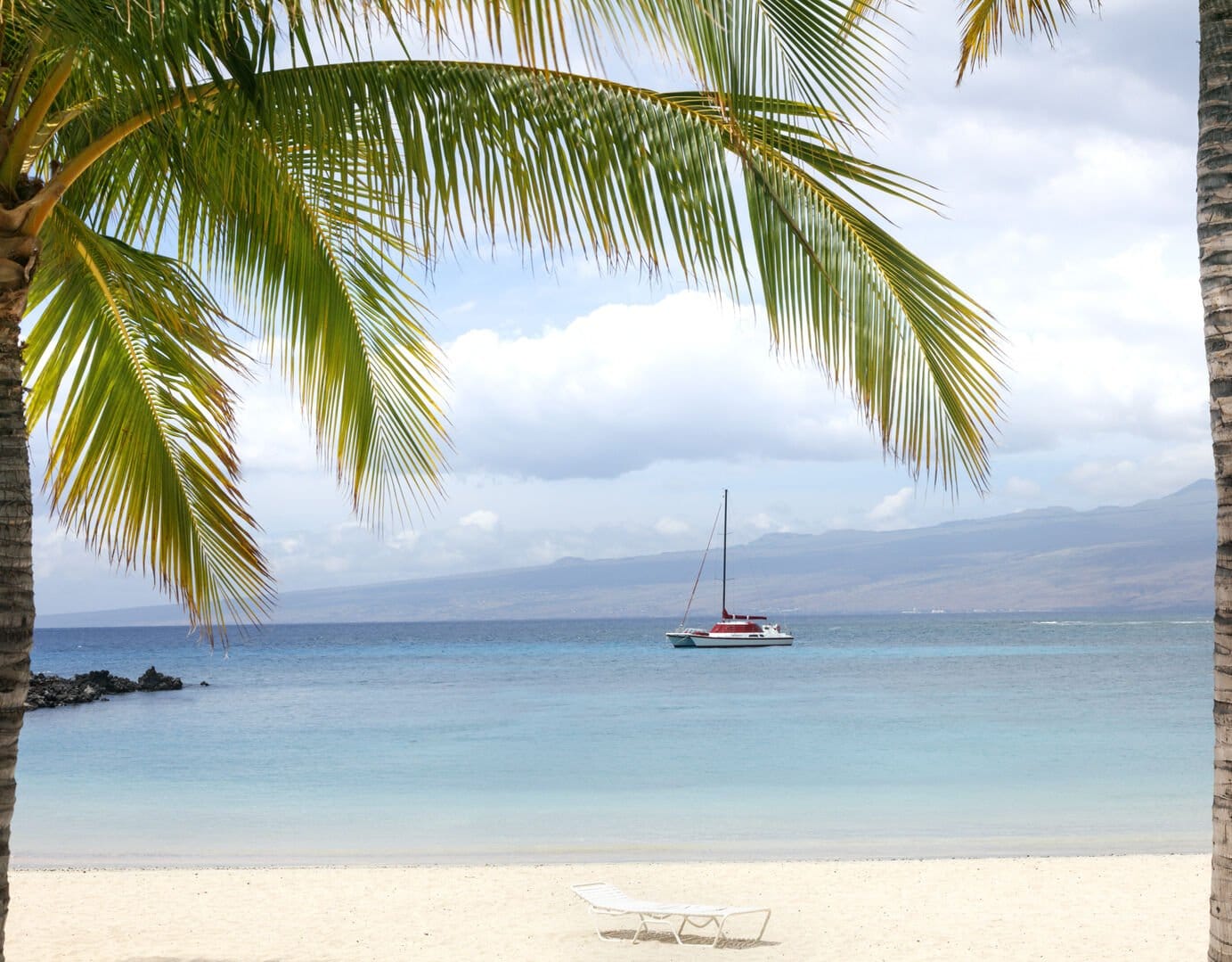 Tropical beach with sailboat, palms.