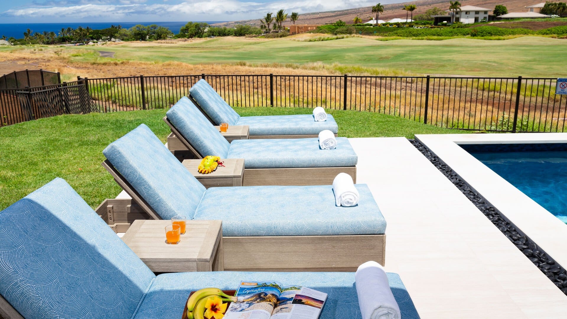 Lounge chairs by pool with view.