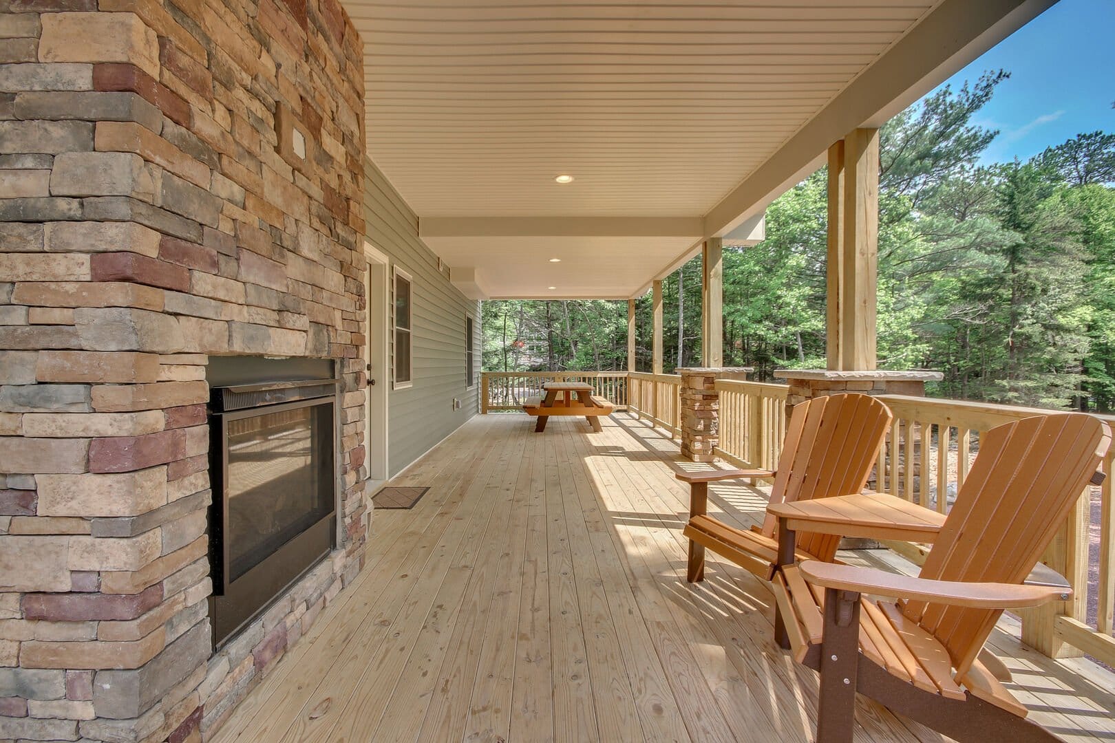 Covered porch with fireplace and chairs.