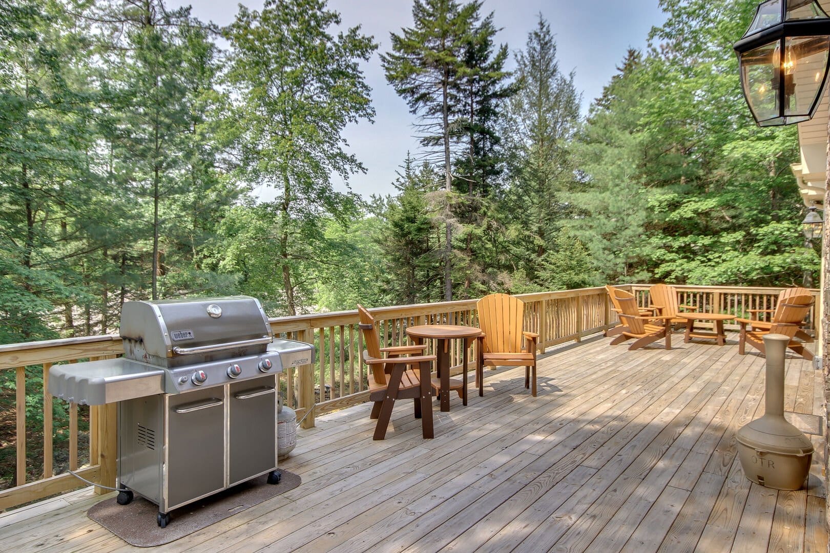 Wooden deck with grill and chairs.