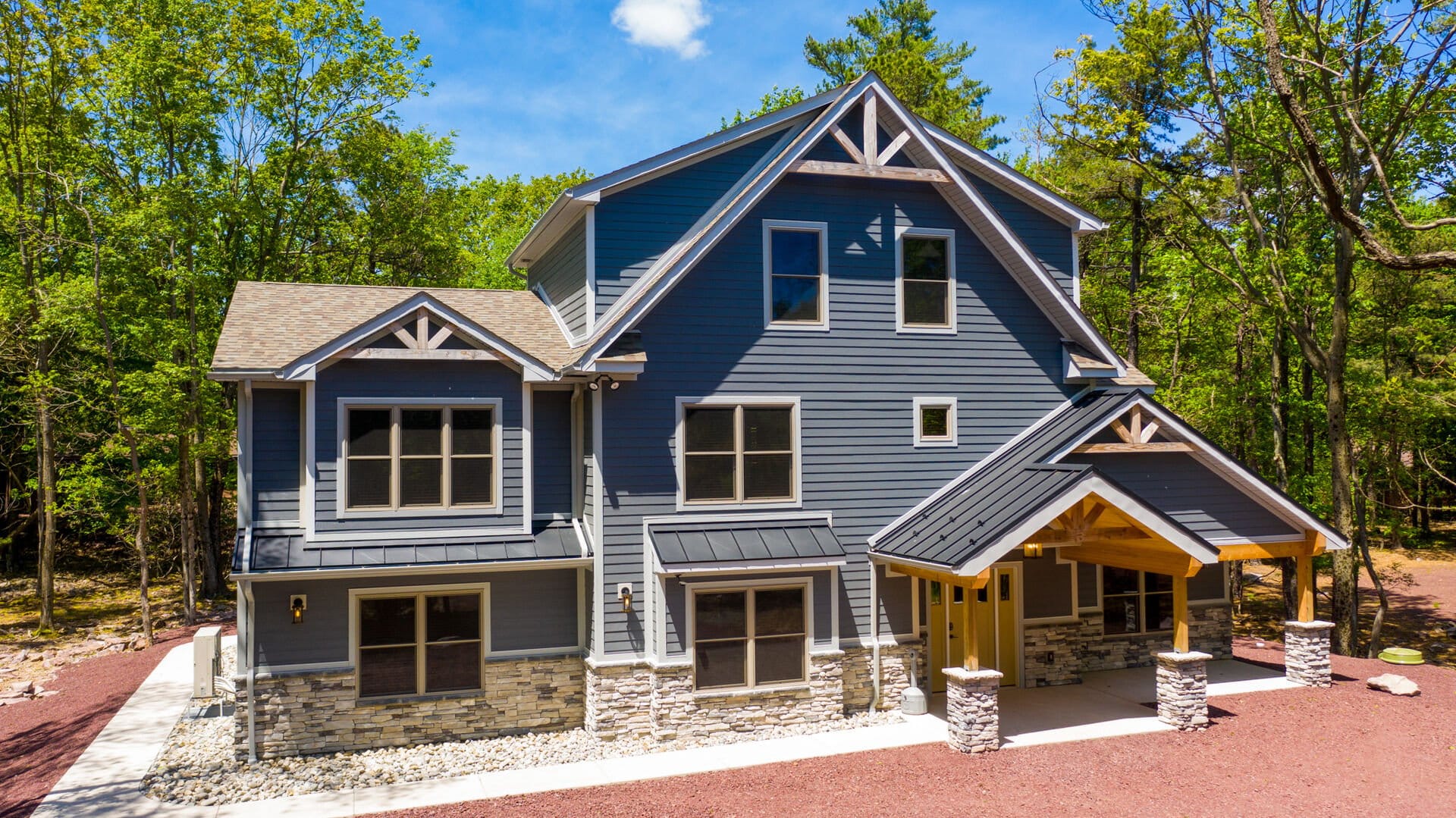 Modern blue house in wooded area.