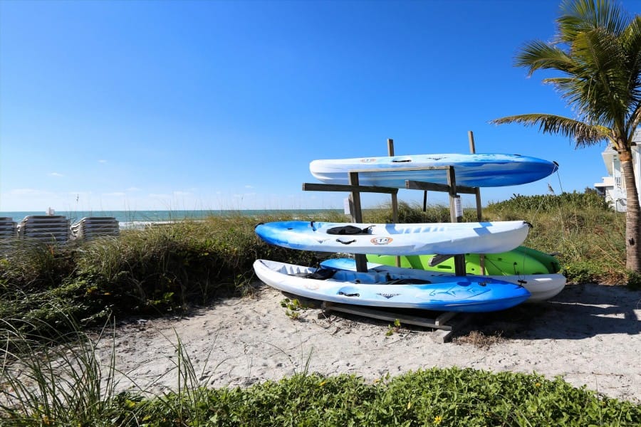 Stacked kayaks on sandy beach.