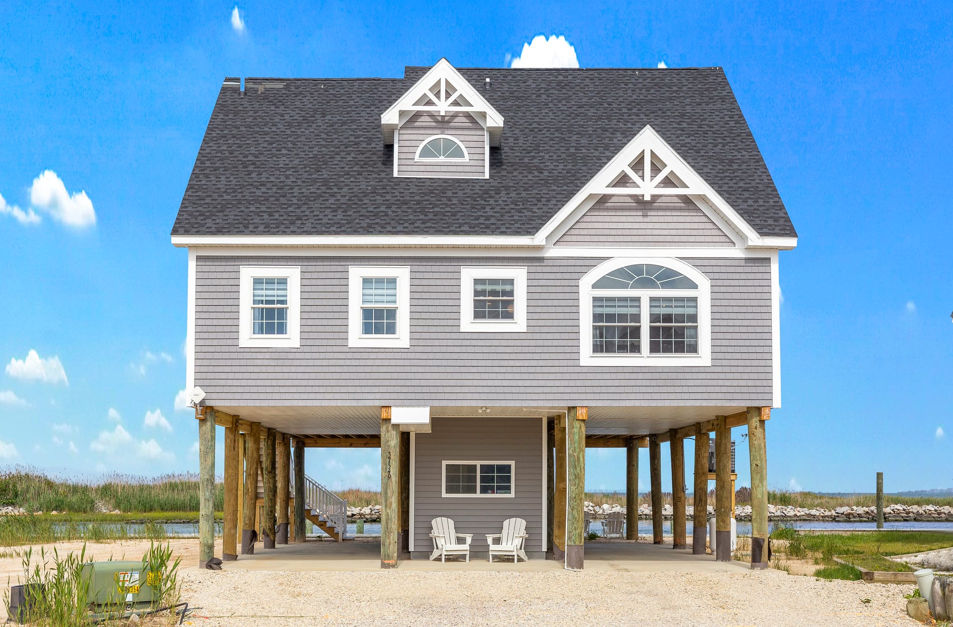 Elevated beach house with chairs underneath.