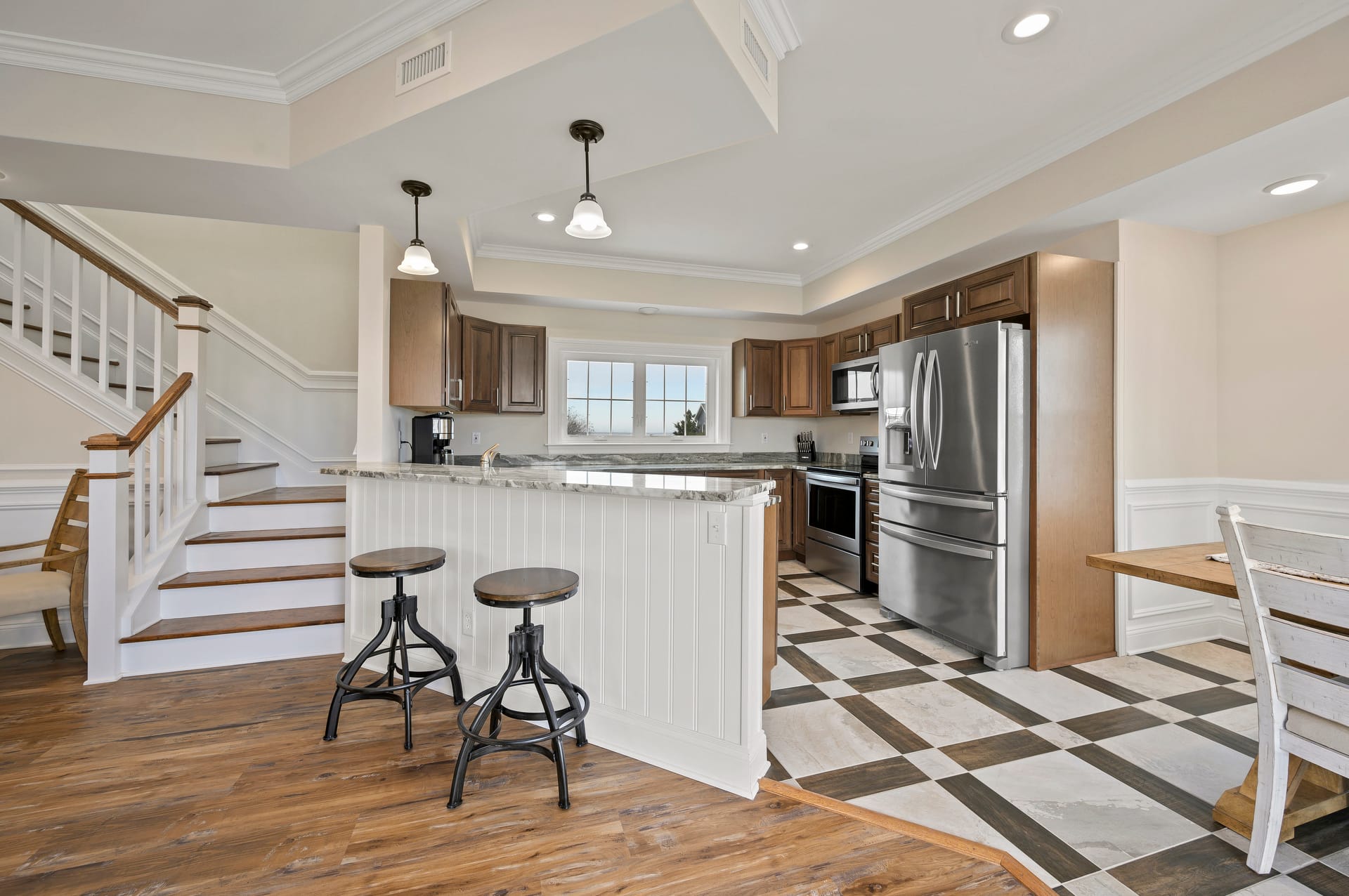 Modern kitchen with stools and staircase.