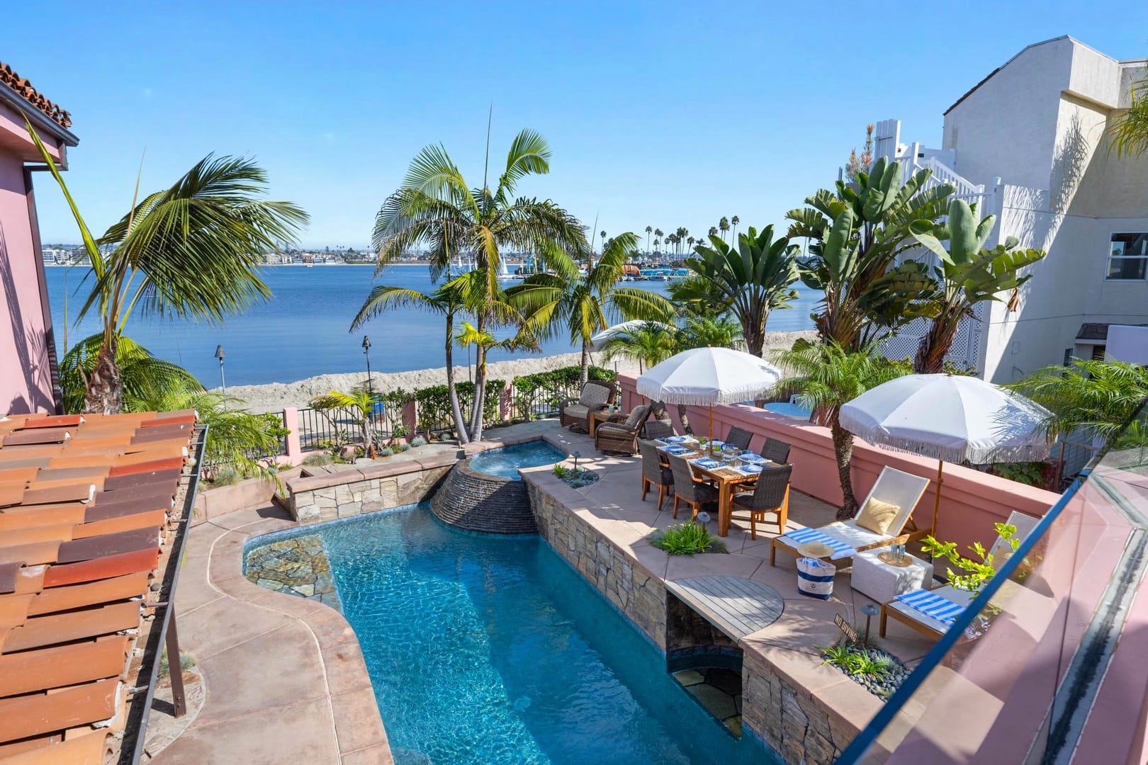 Beachfront patio with pool and palm.