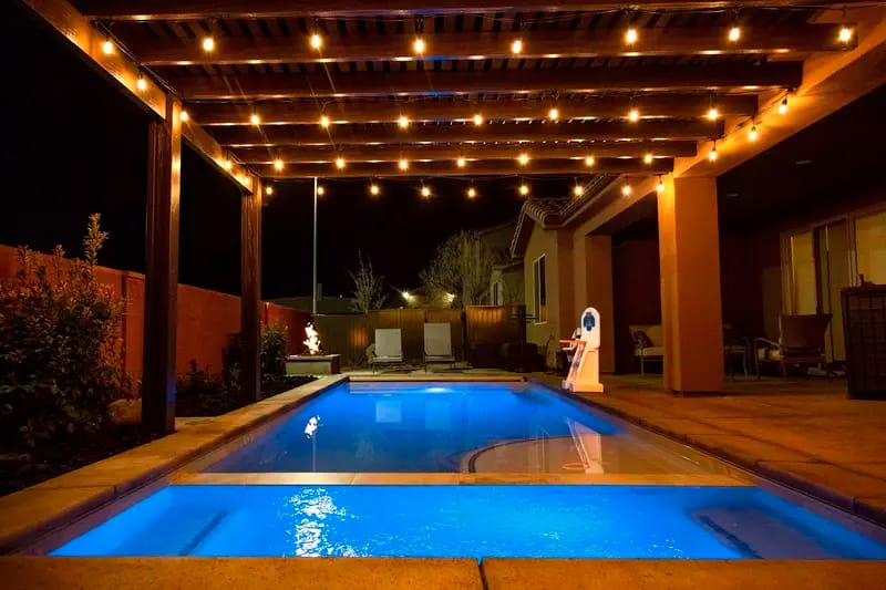 Lit backyard pool at night.