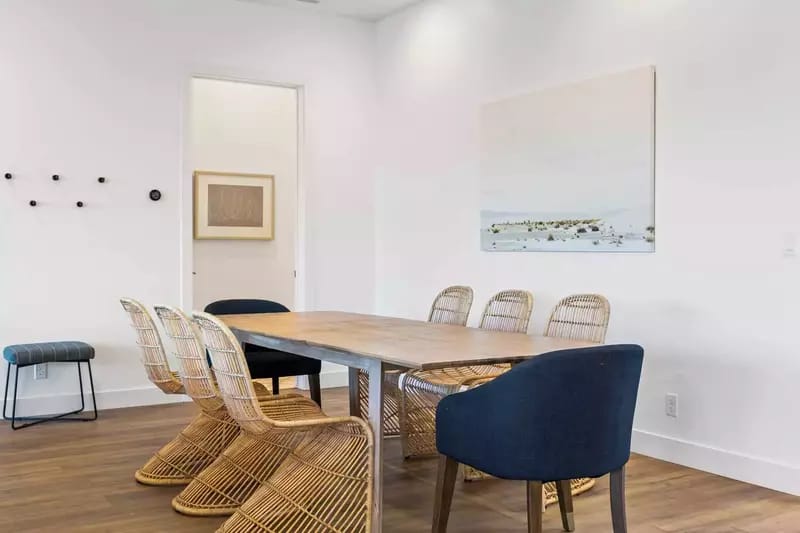 Minimalist dining room with wicker chairs.