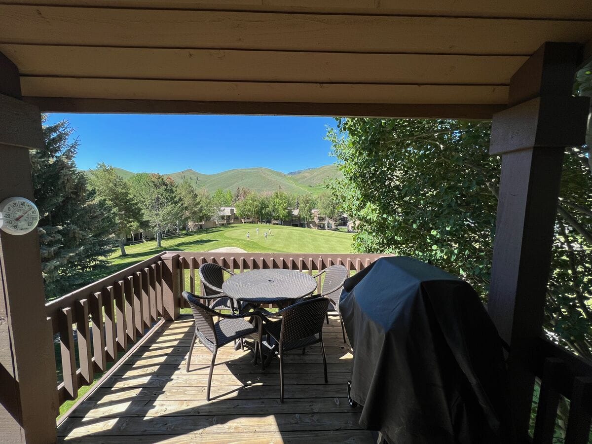 Balcony with table overlooking greenery.