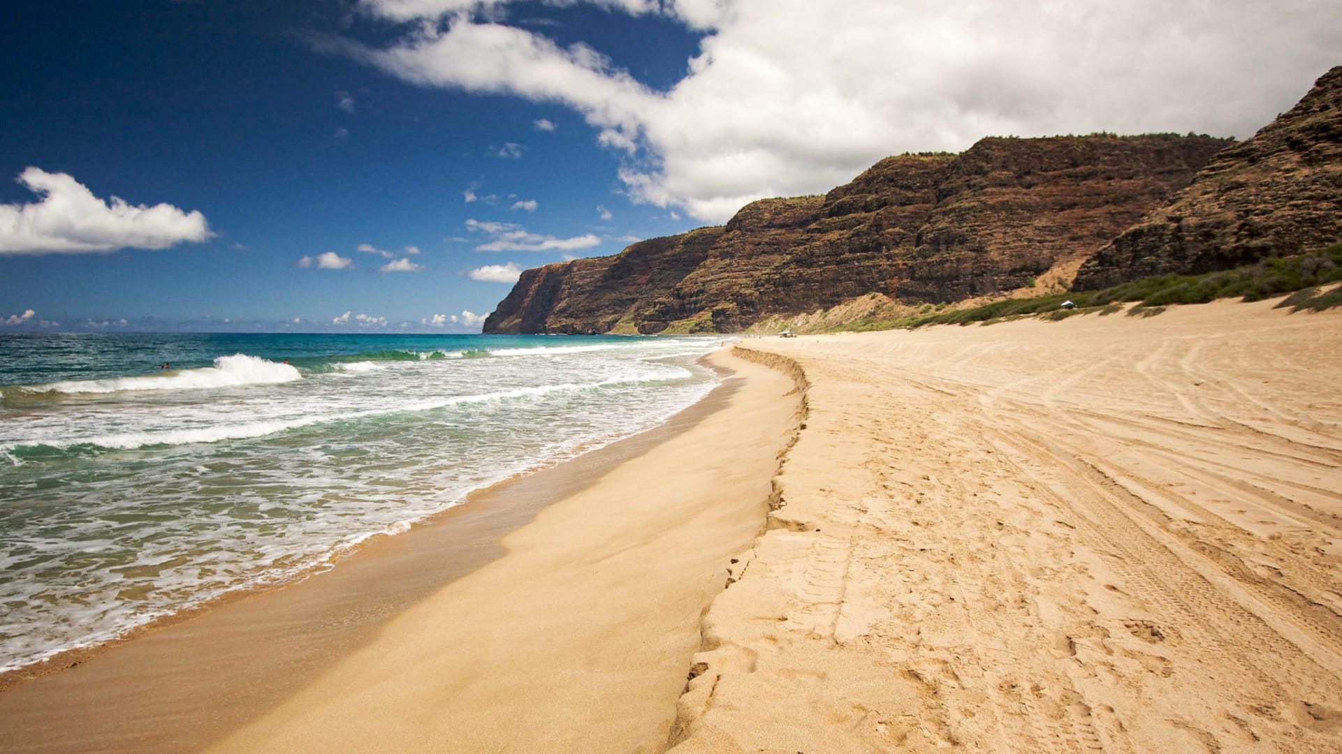 Beach with waves and rocky cliffs.