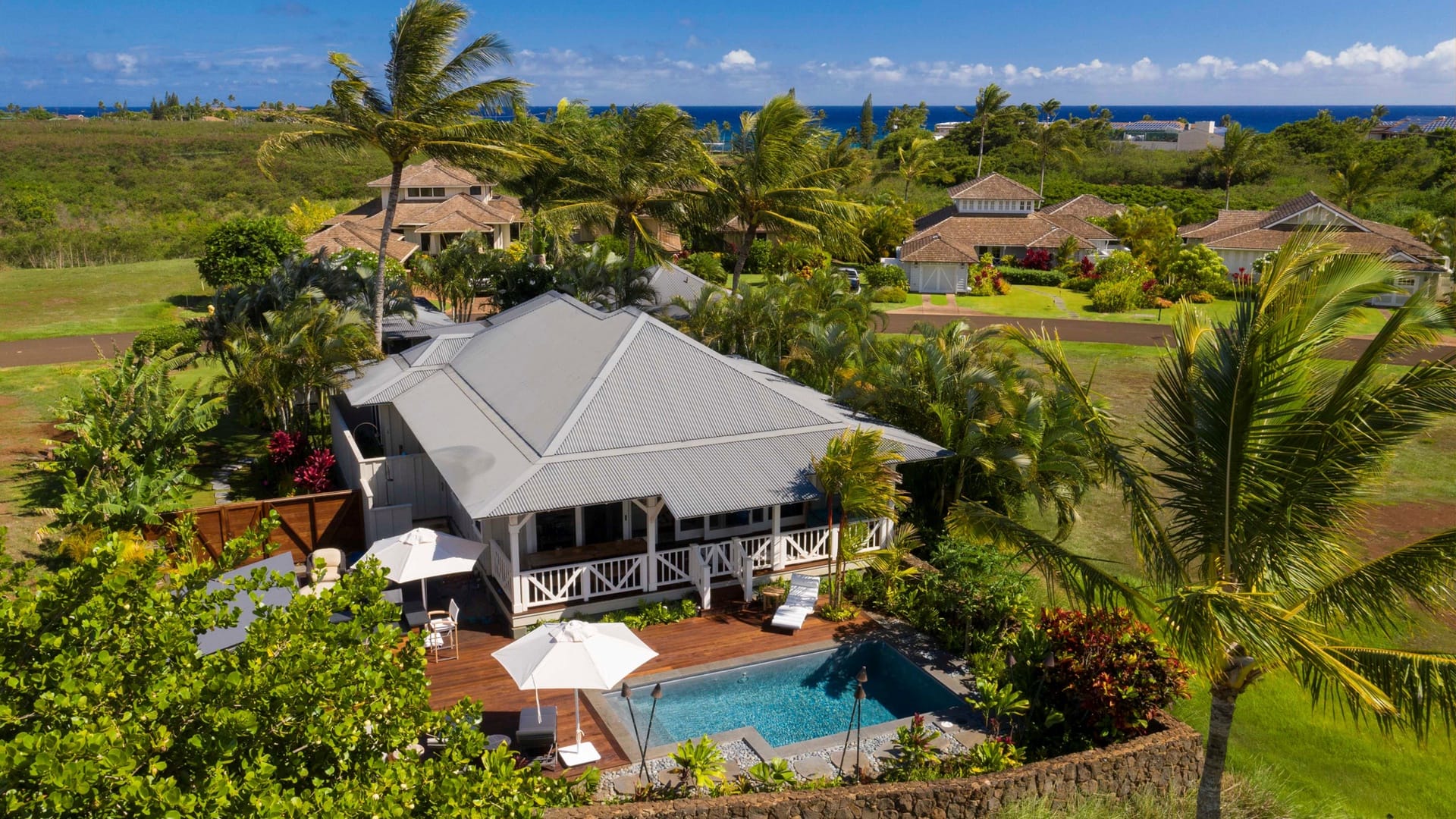 Tropical house with pool, ocean backdrop.