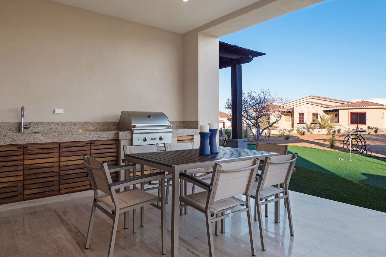 Outdoor patio with table and grill.