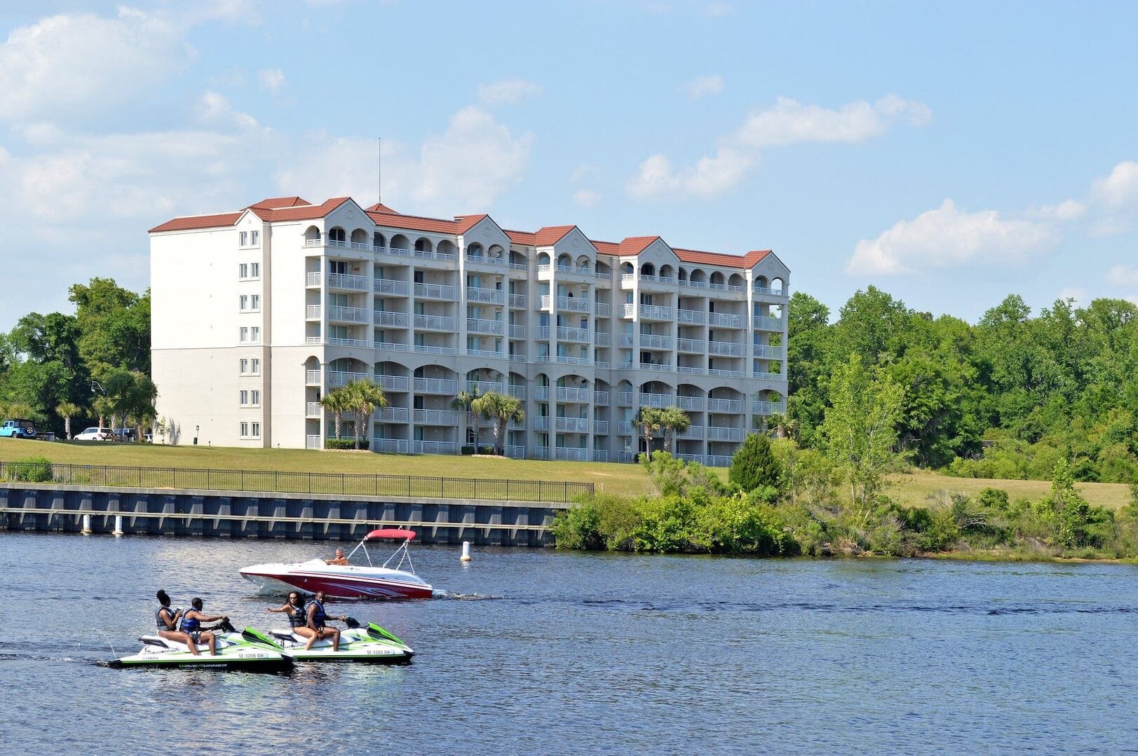 Jetskis and boat near riverside building.