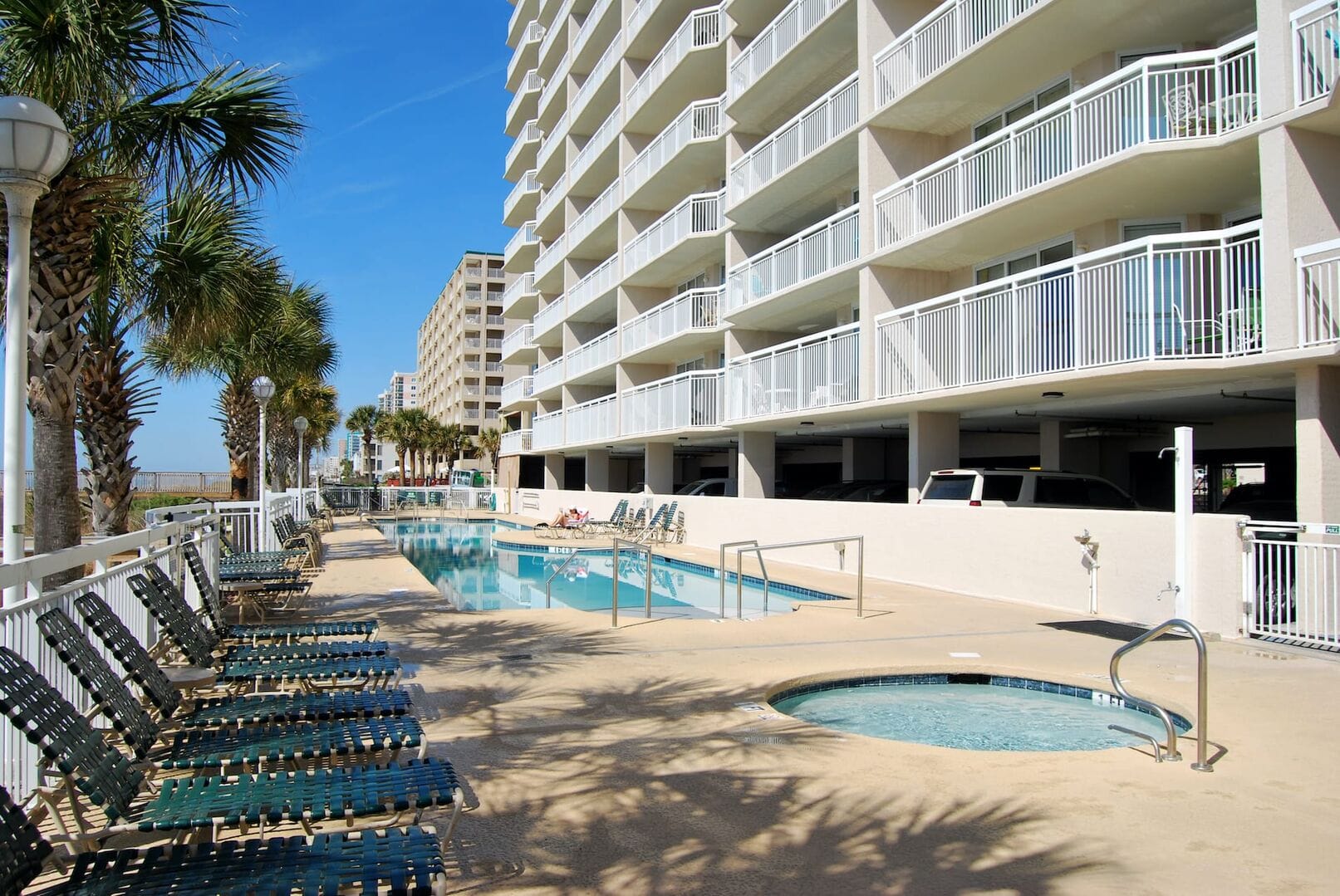 Poolside by beachfront high-rise building.