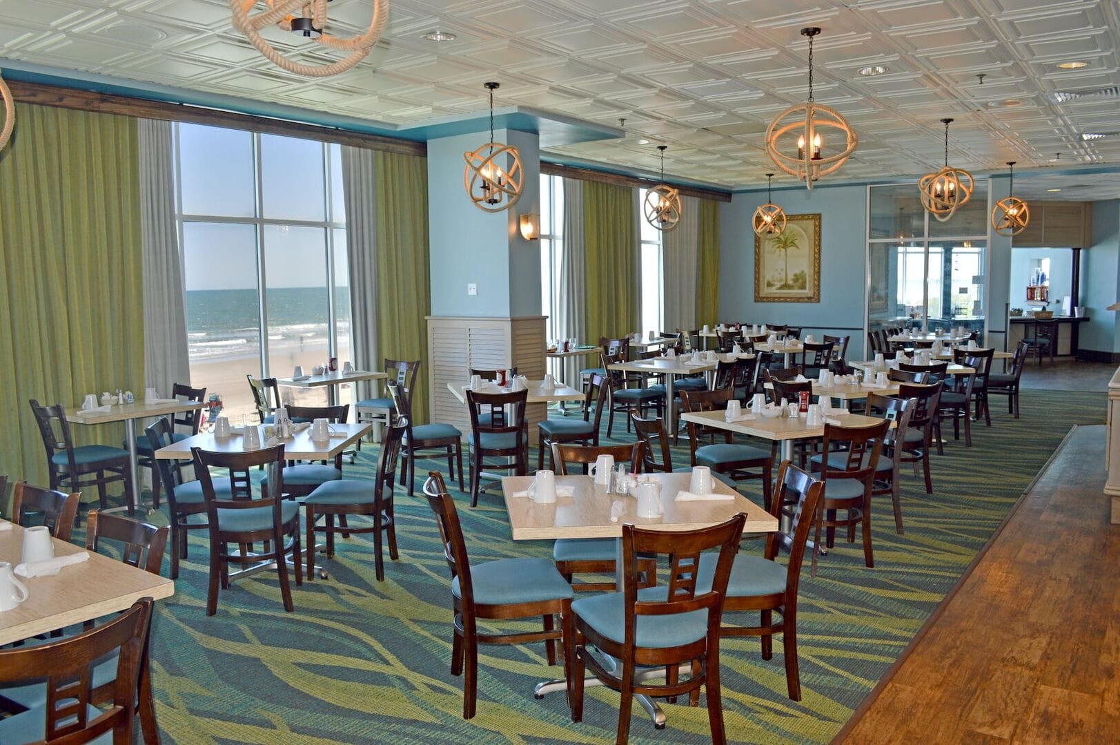 Ocean-view restaurant with empty tables.