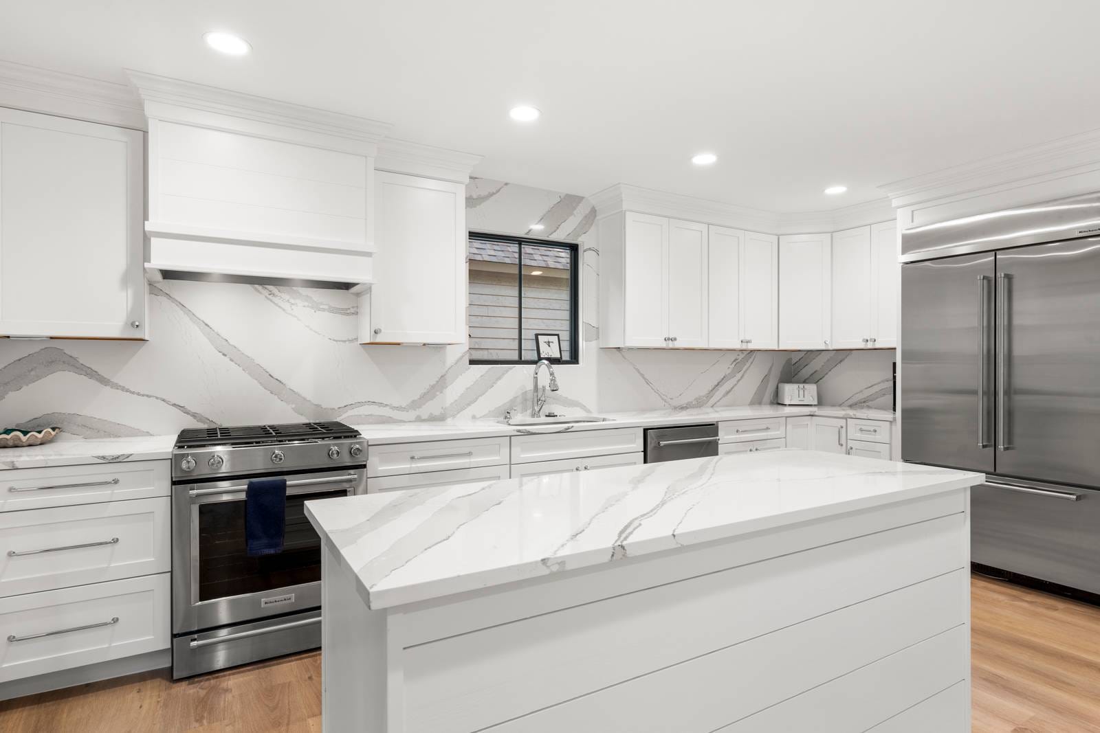 Modern white kitchen with stainless appliances.