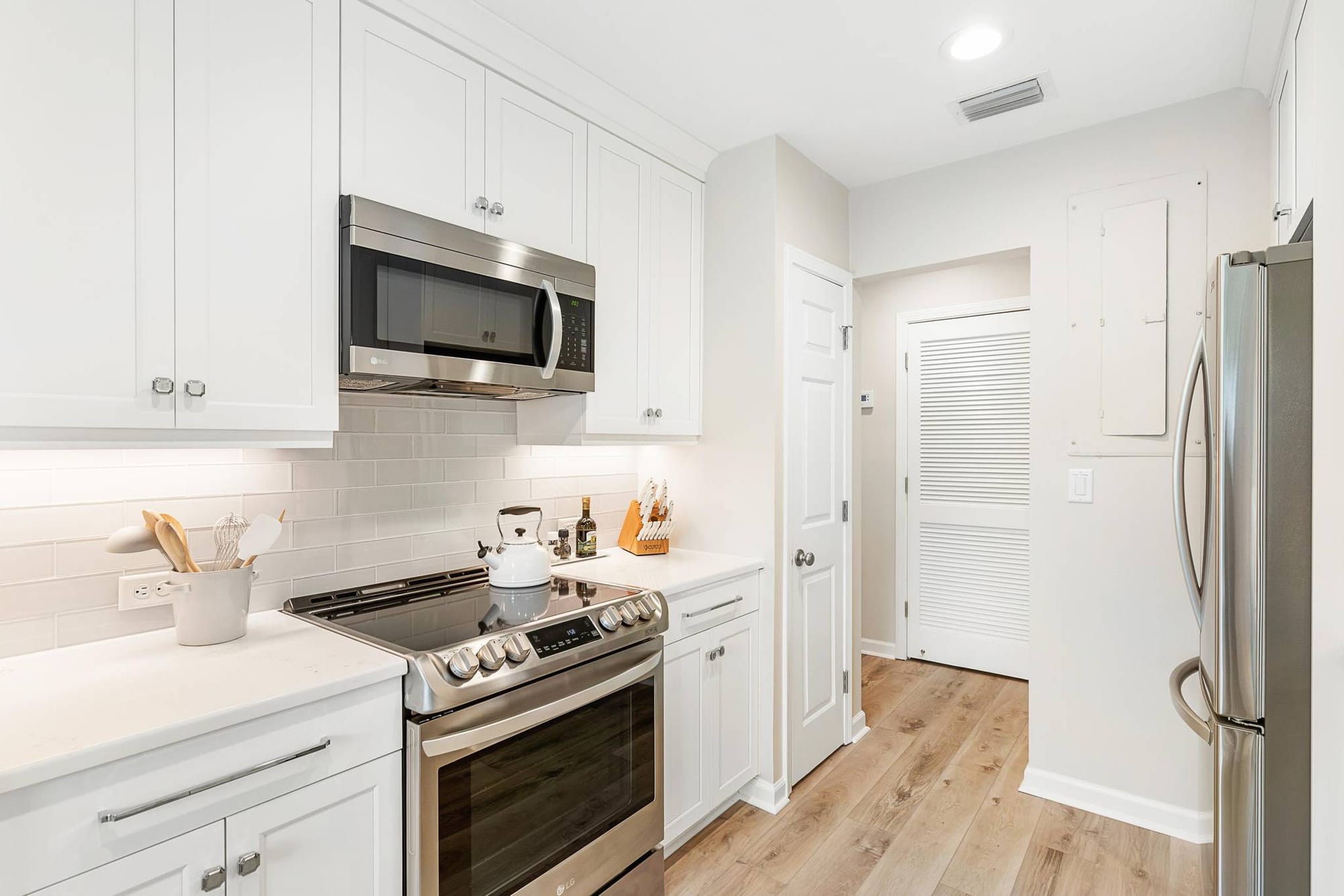 Modern white kitchen with stainless appliances.