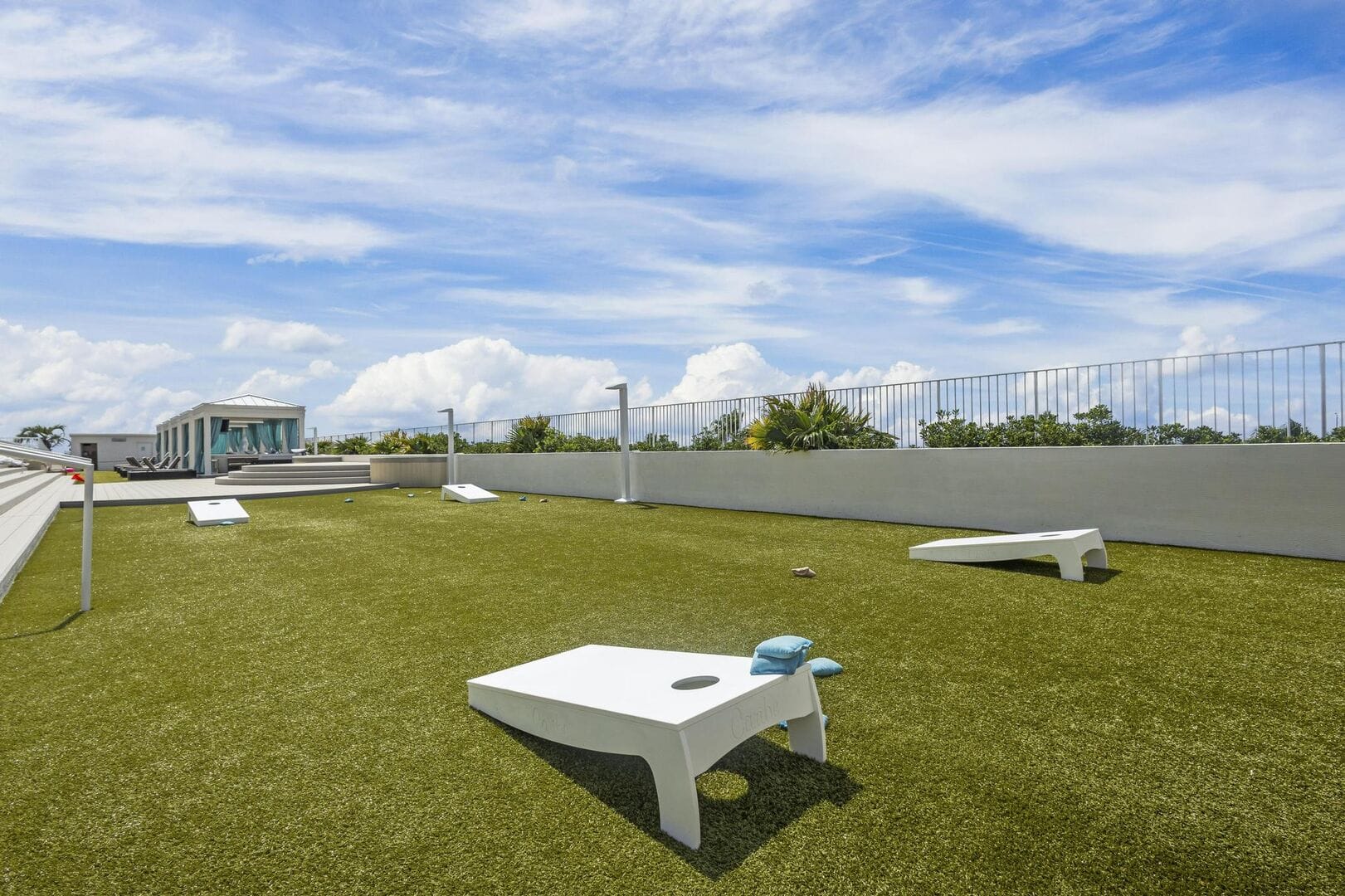 Rooftop cornhole game under sky.