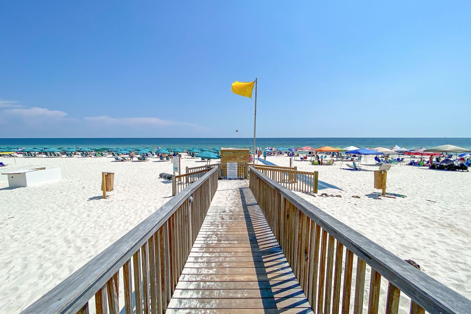 Boardwalk leading to crowded beach.