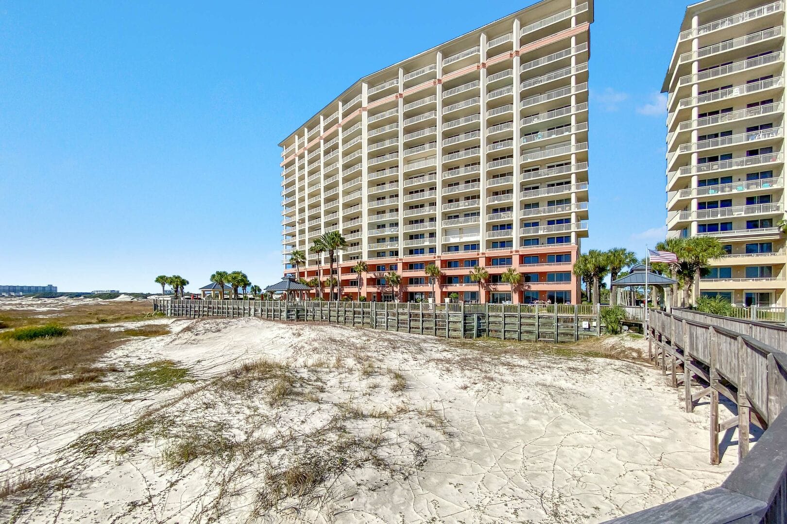 Beachfront hotel with boardwalk, sky.