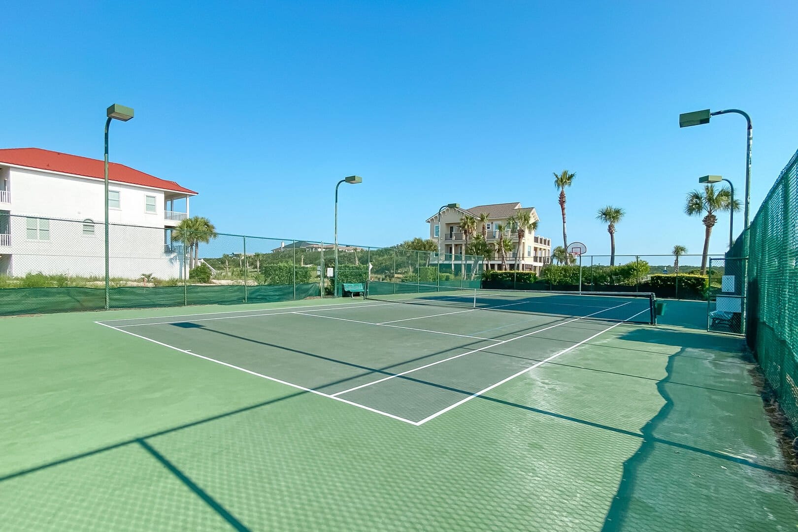 Outdoor tennis court with surrounding buildings.