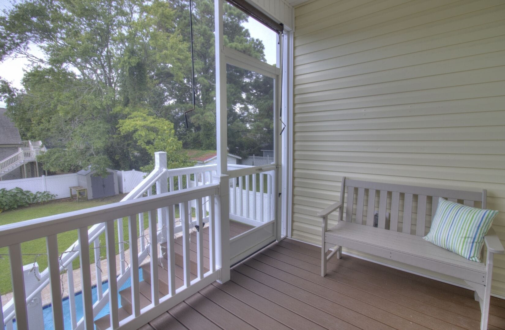 Screened porch with wooden bench.