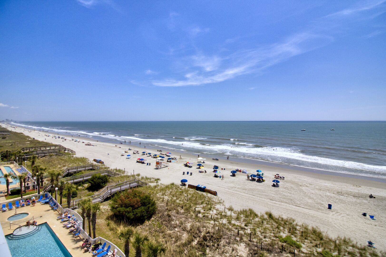 Sunny beach with umbrellas and ocean.