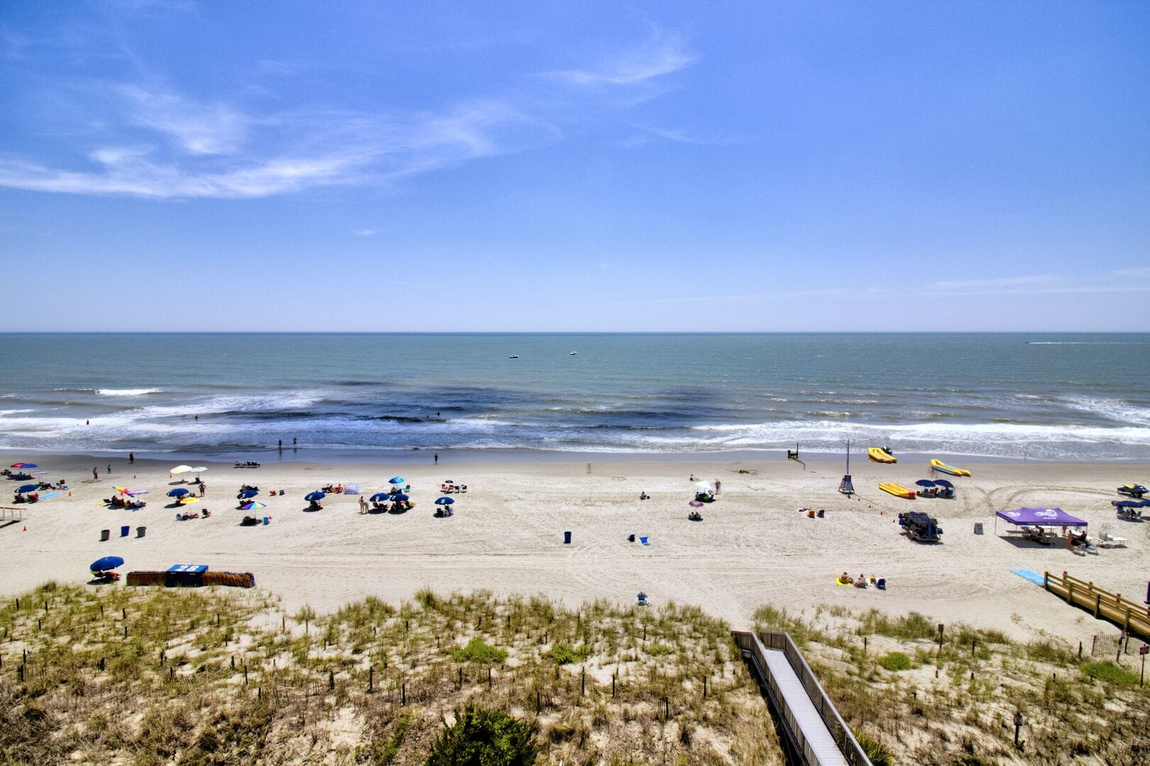 Sunny beach with umbrellas and ocean.