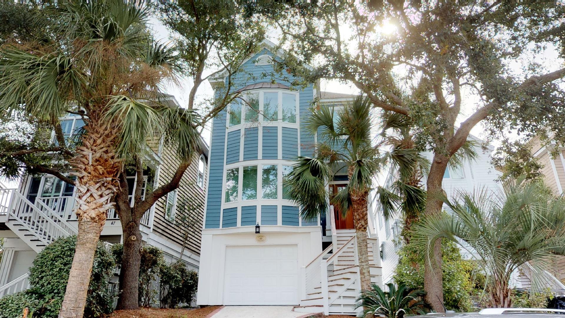 Blue house surrounded by palm trees.