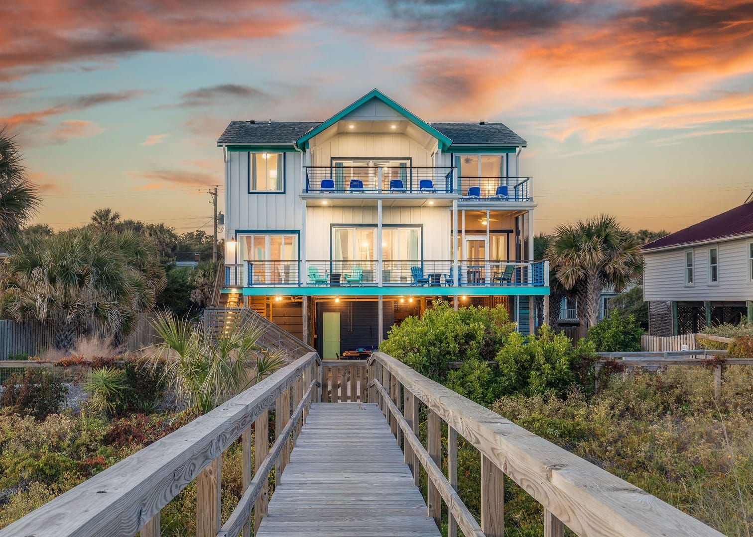 Beach house with walkway, sunset sky.