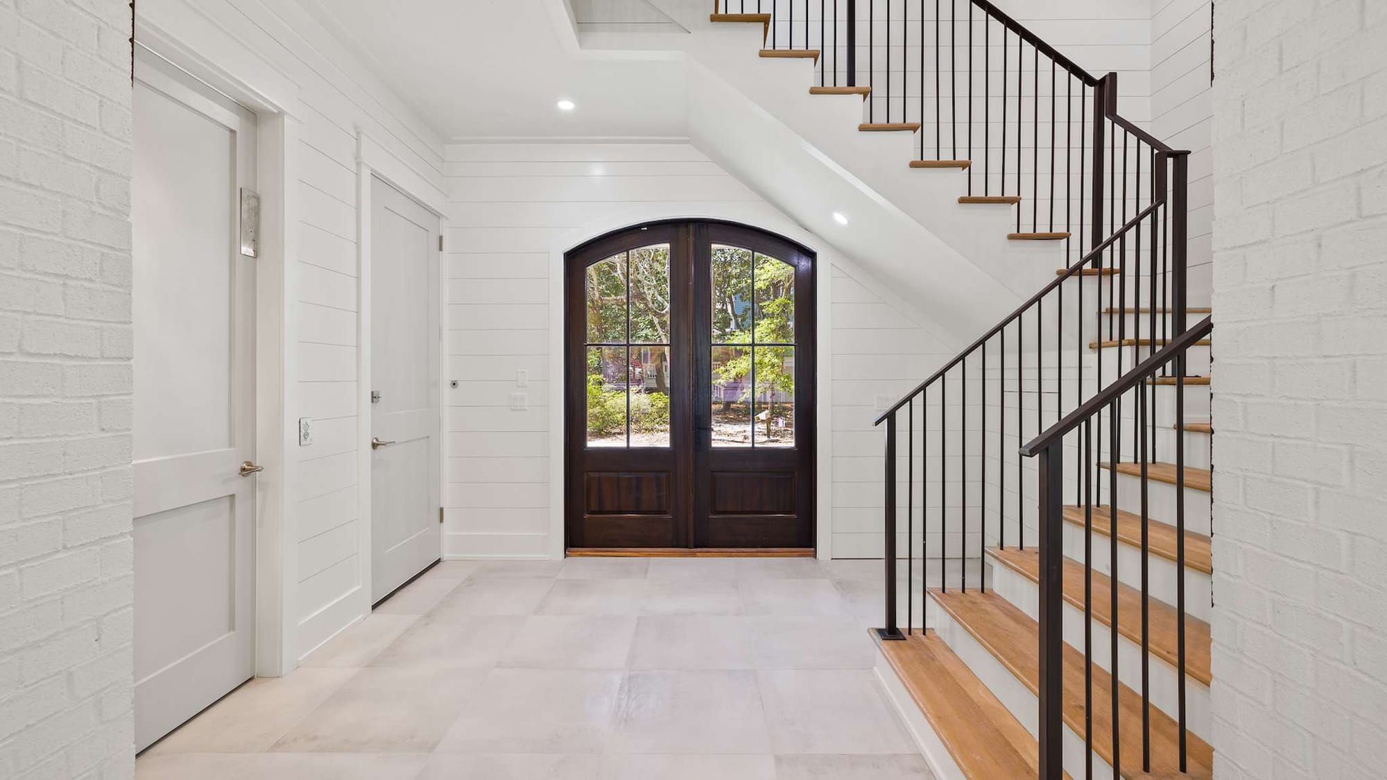 White foyer with wooden staircase.