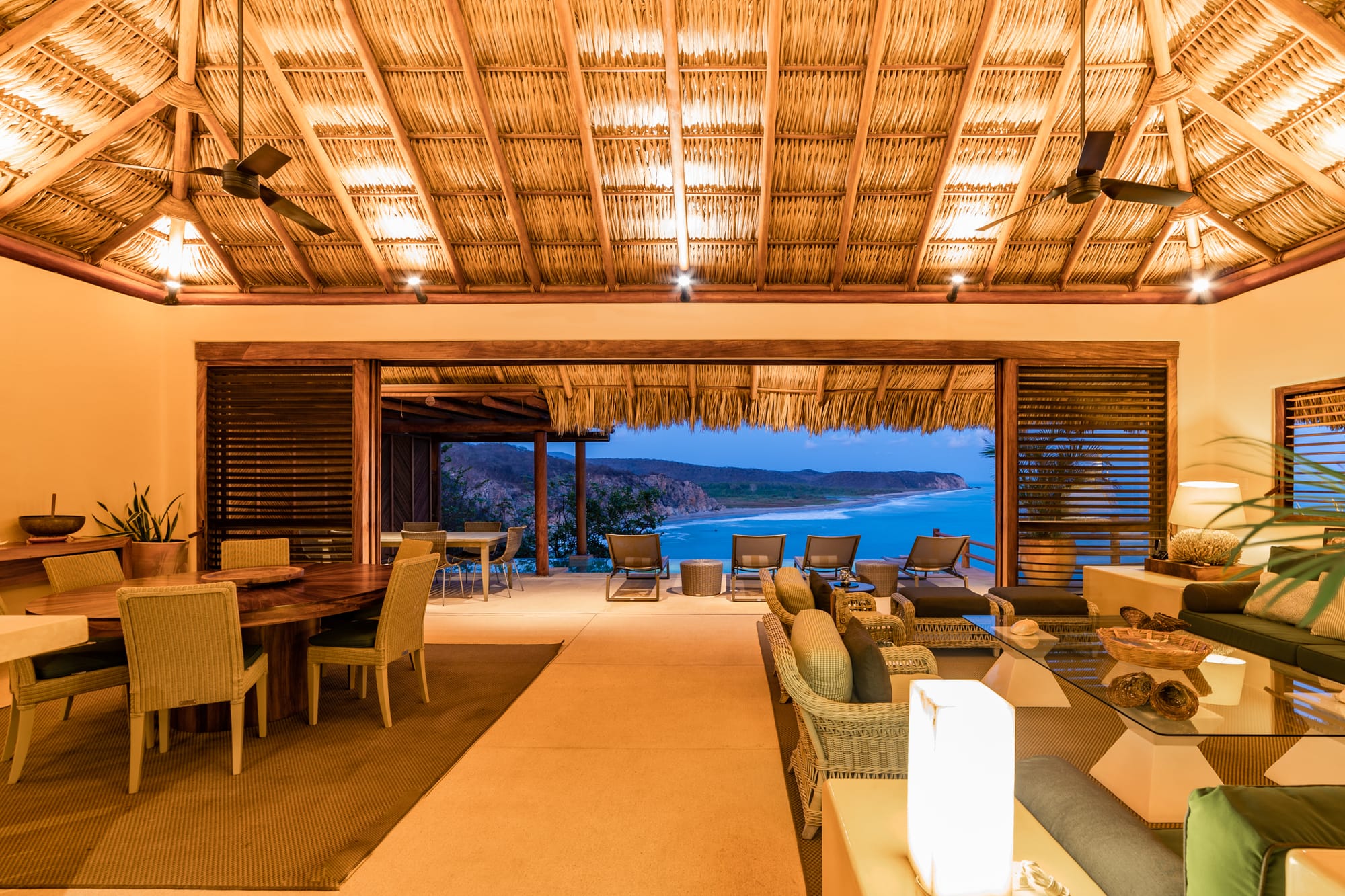 Open-air, thatched-roof beach lounge.