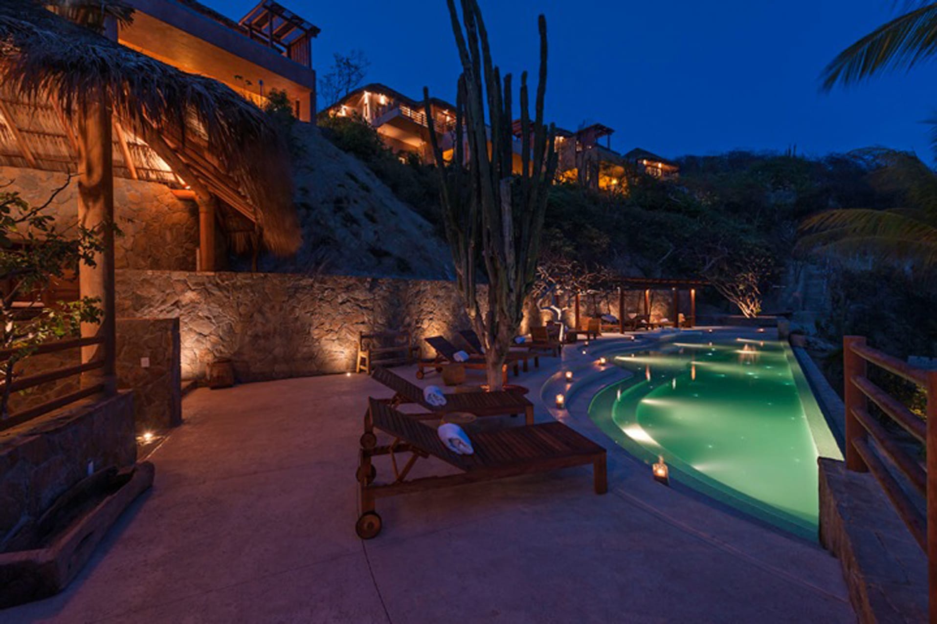 Nighttime poolside with candles lit.