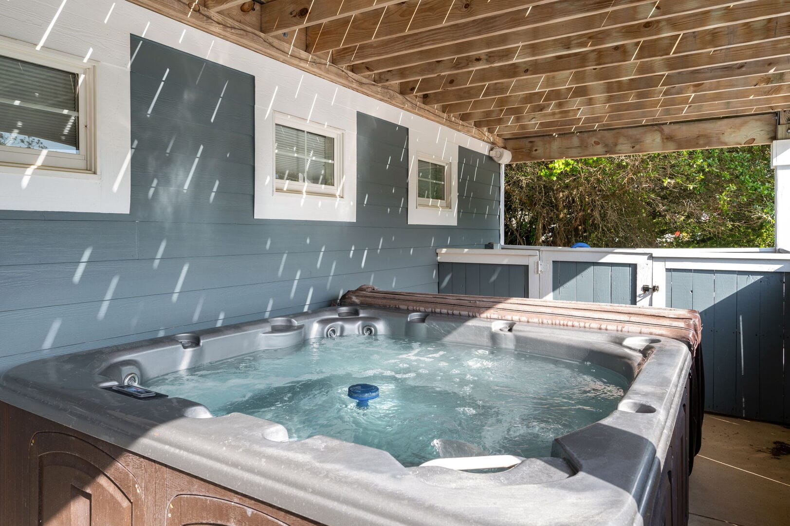 Outdoor hot tub under wooden pergola.