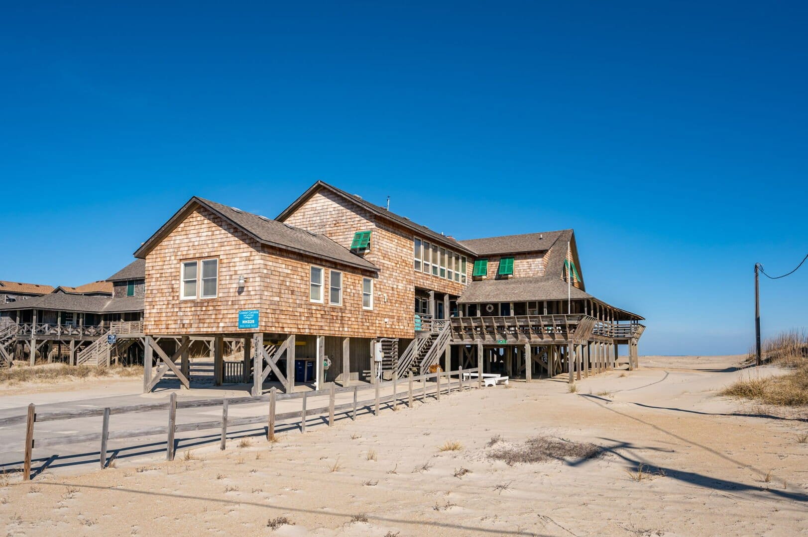 Wooden beach house on sandy shore.