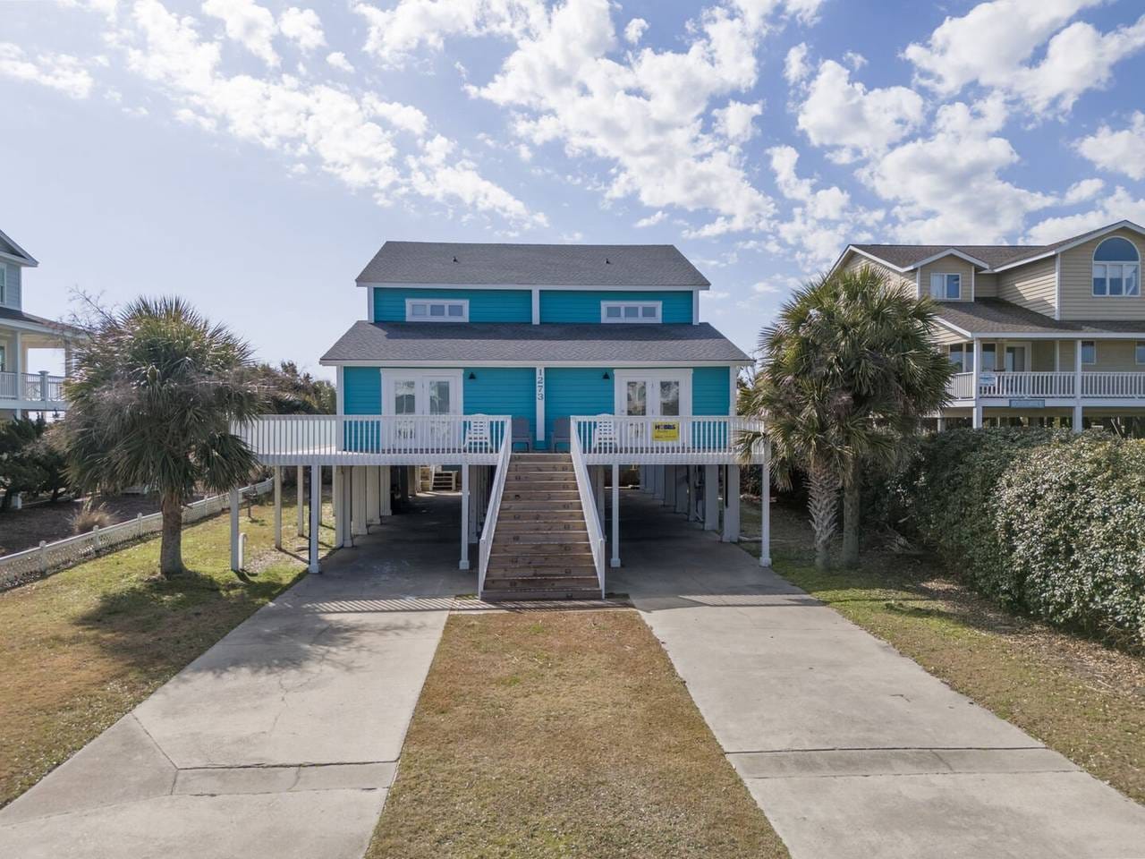 Elevated blue house with driveway.