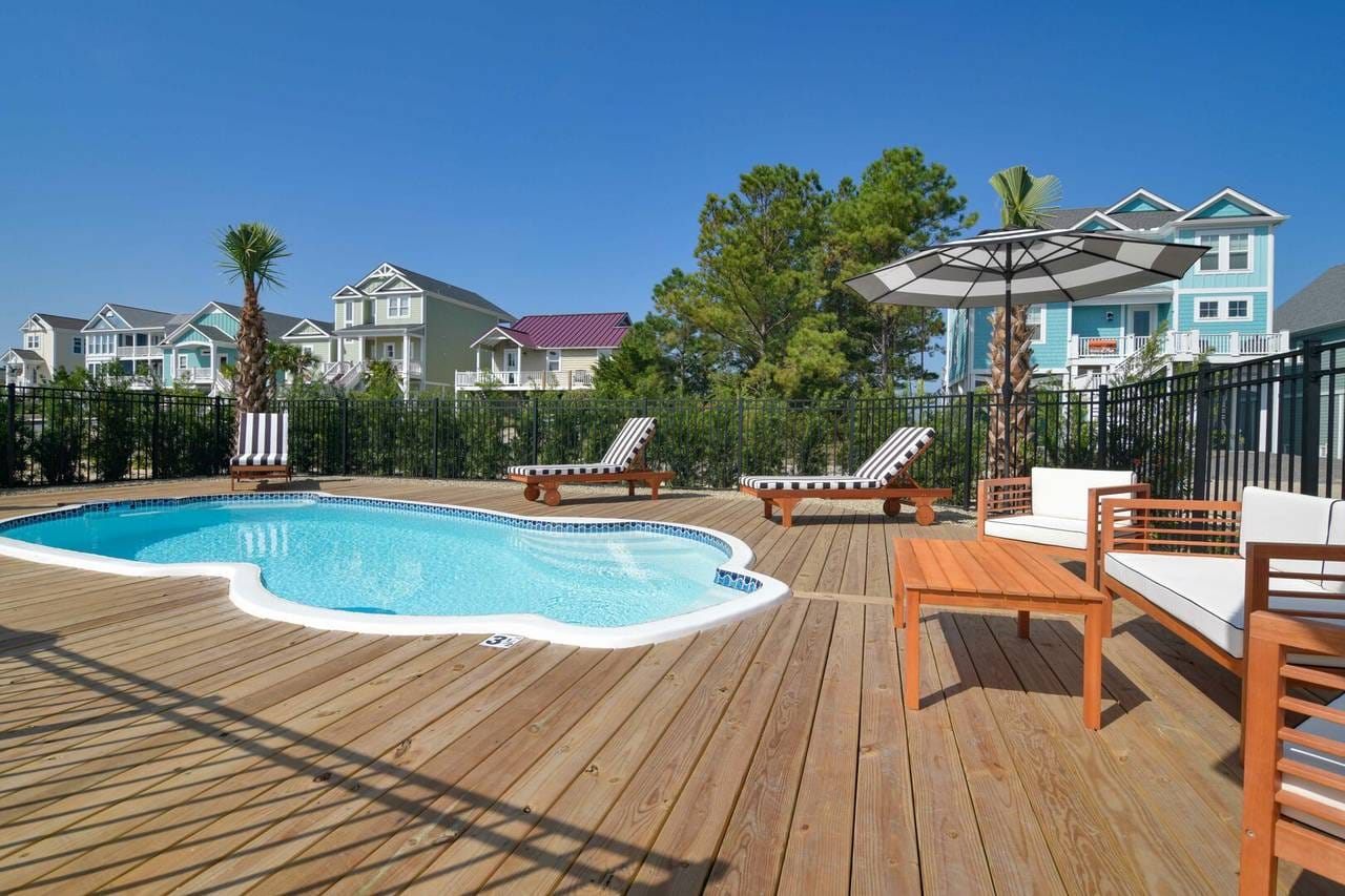 Poolside deck with loungers, umbrella.