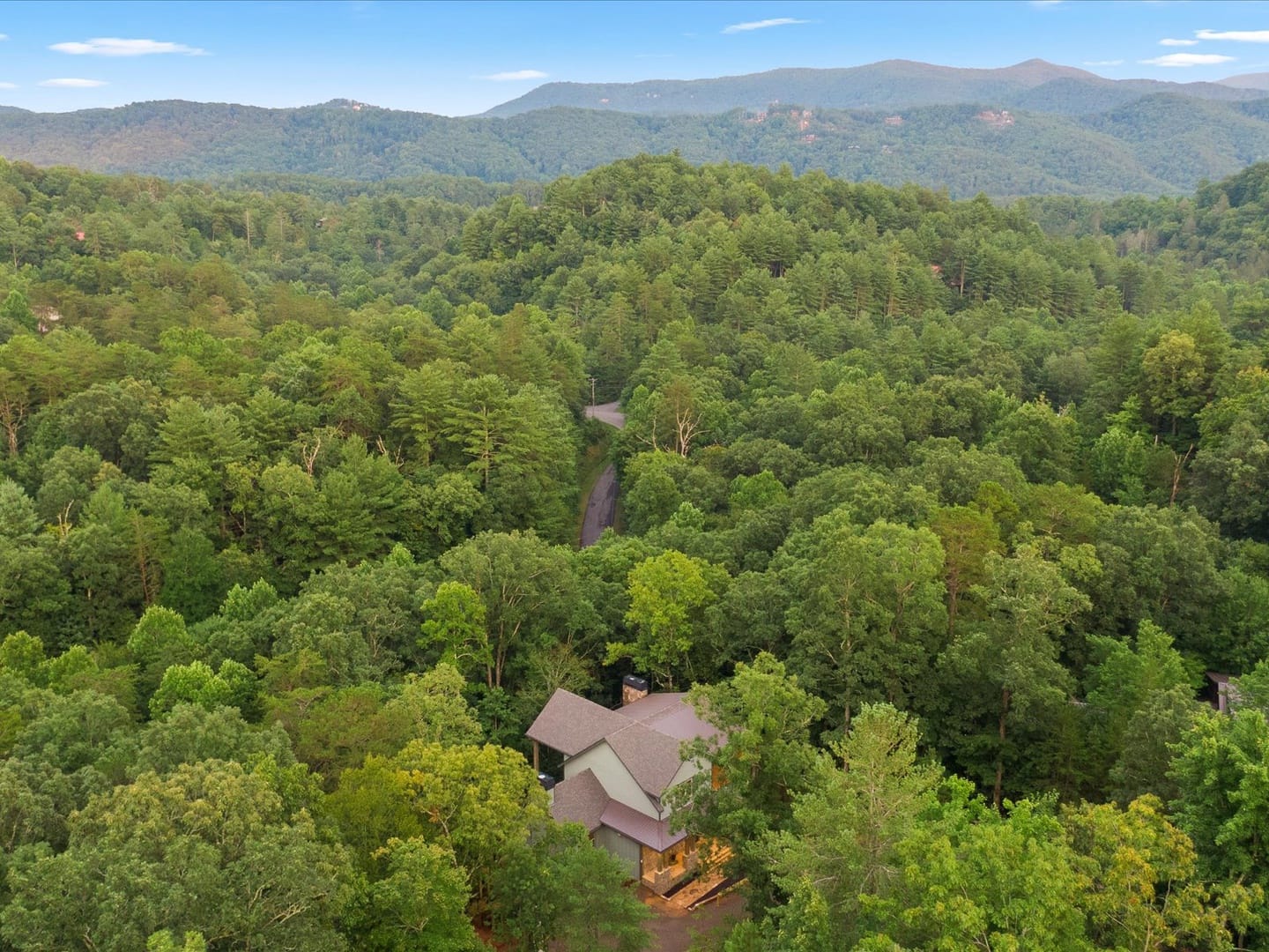 House surrounded by forested mountains.