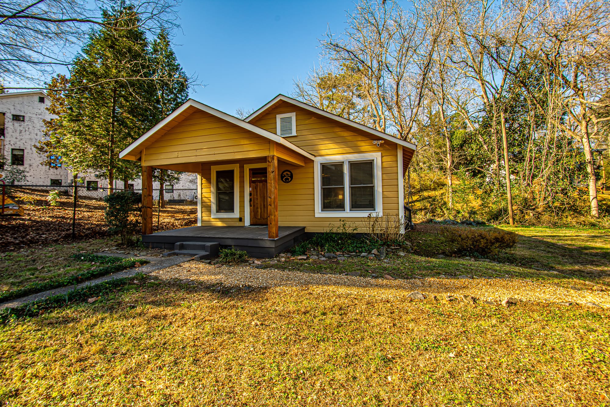 Small yellow house, wooded background.