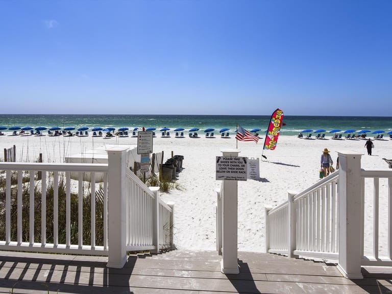 Beach entrance with chairs and umbrellas.