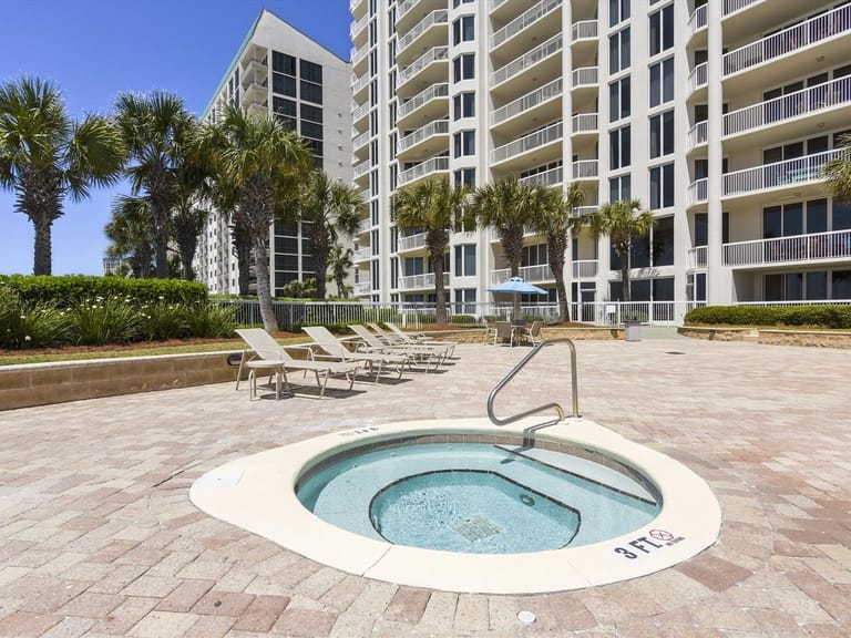 Outdoor jacuzzi, lounge chairs, palm trees.