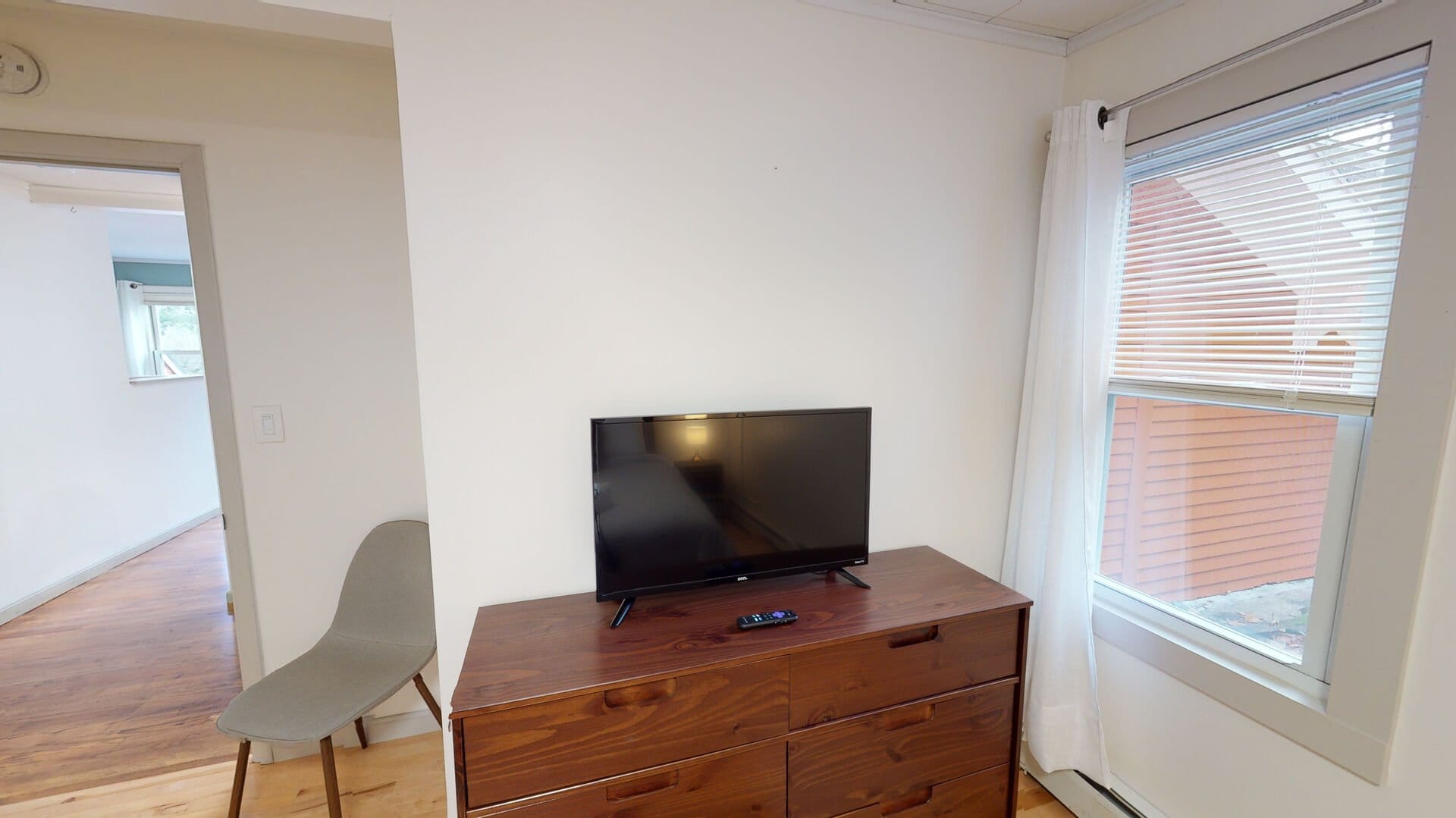 TV on dresser, next to window.