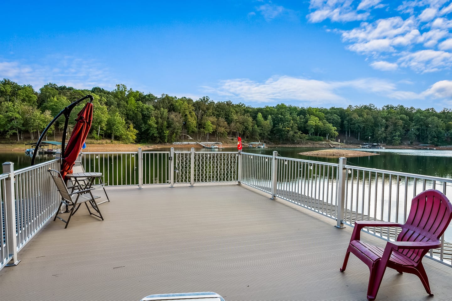 Lakeside deck with chairs, trees.