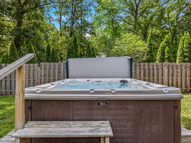 Outdoor hot tub in fenced yard.