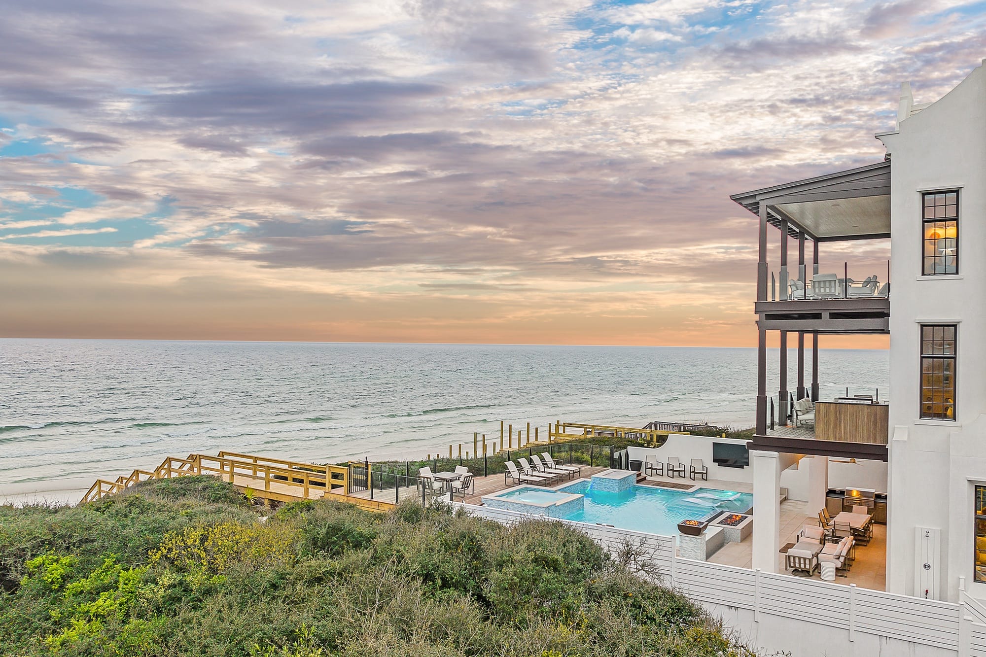 Beachfront house with pool, sunset.