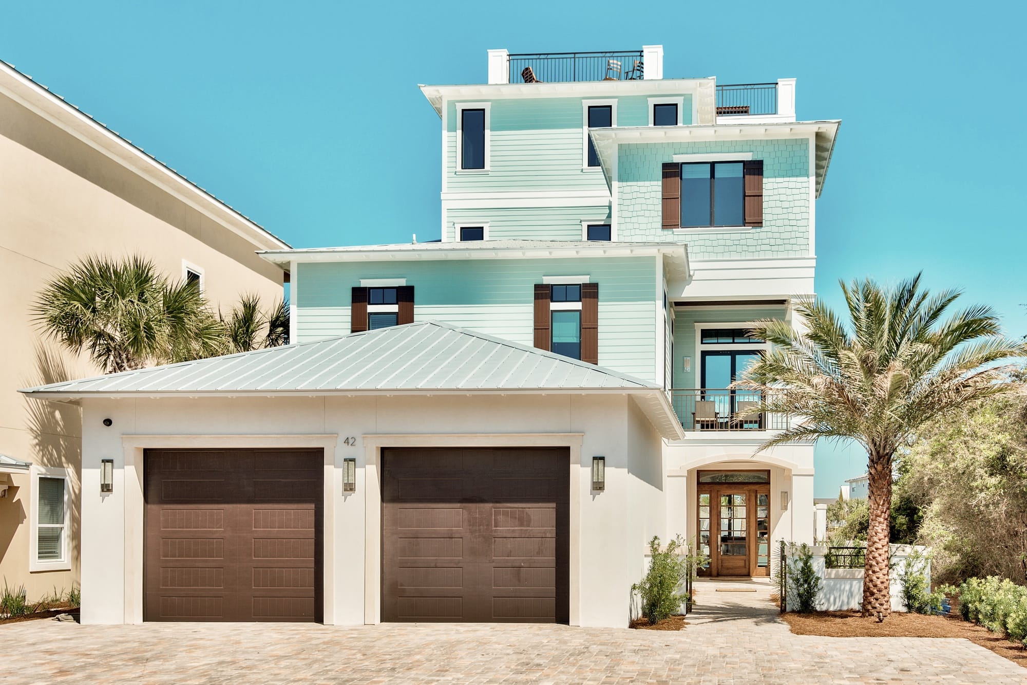 Three-story house with palm trees.