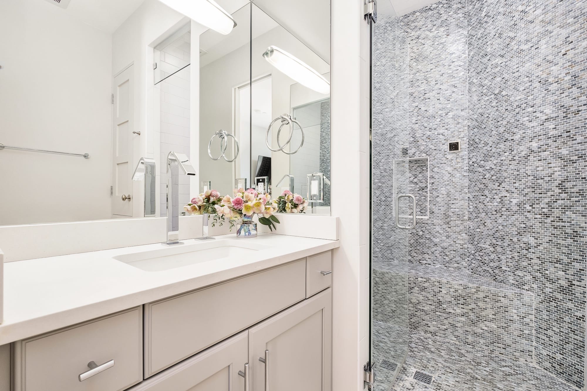 Modern bathroom with floral arrangement.