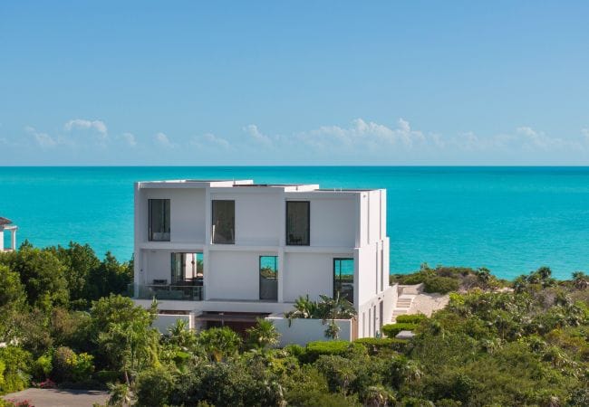 Modern house overlooking turquoise ocean.